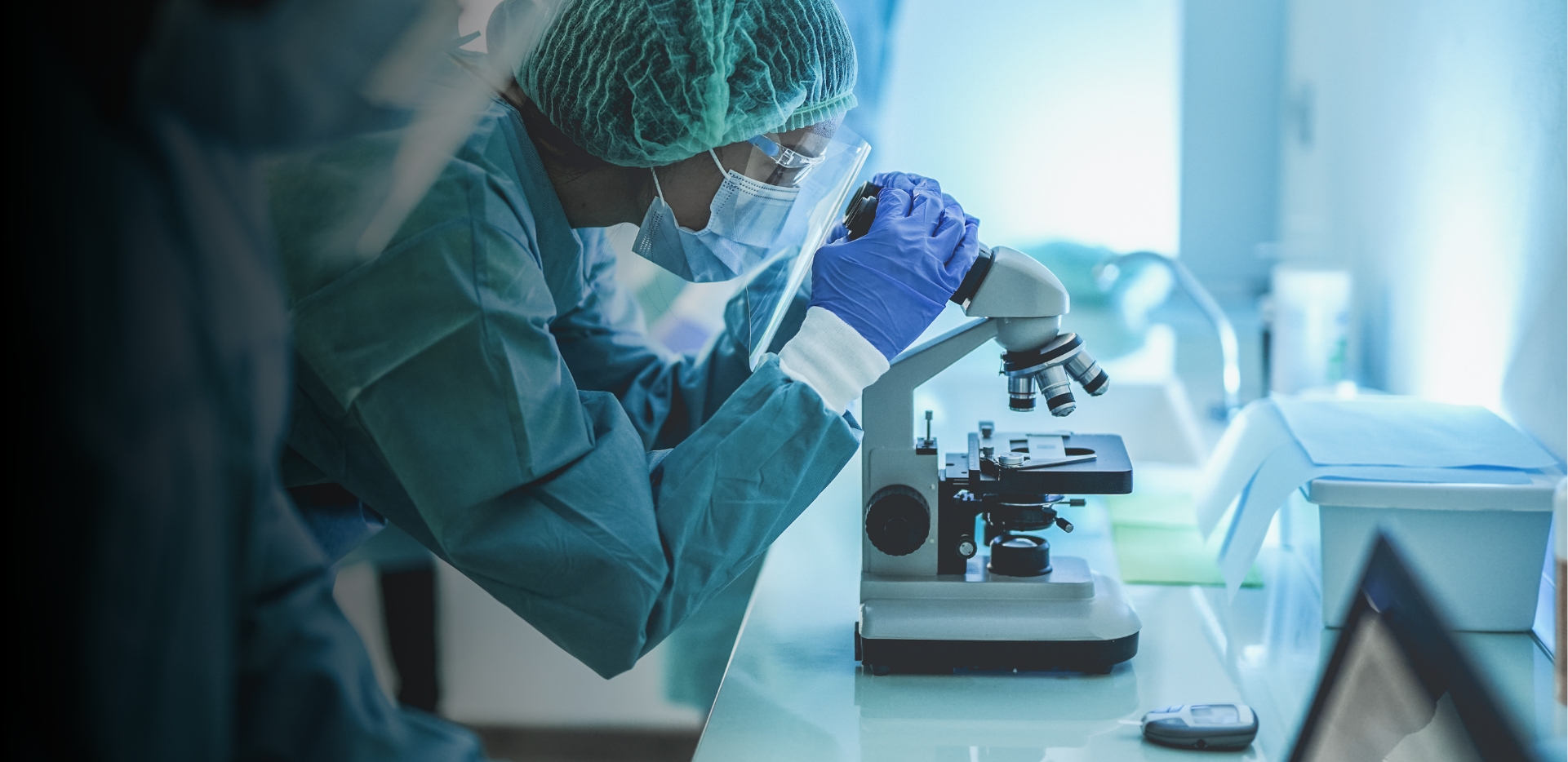 A scientist looking into a microscope viewfinder