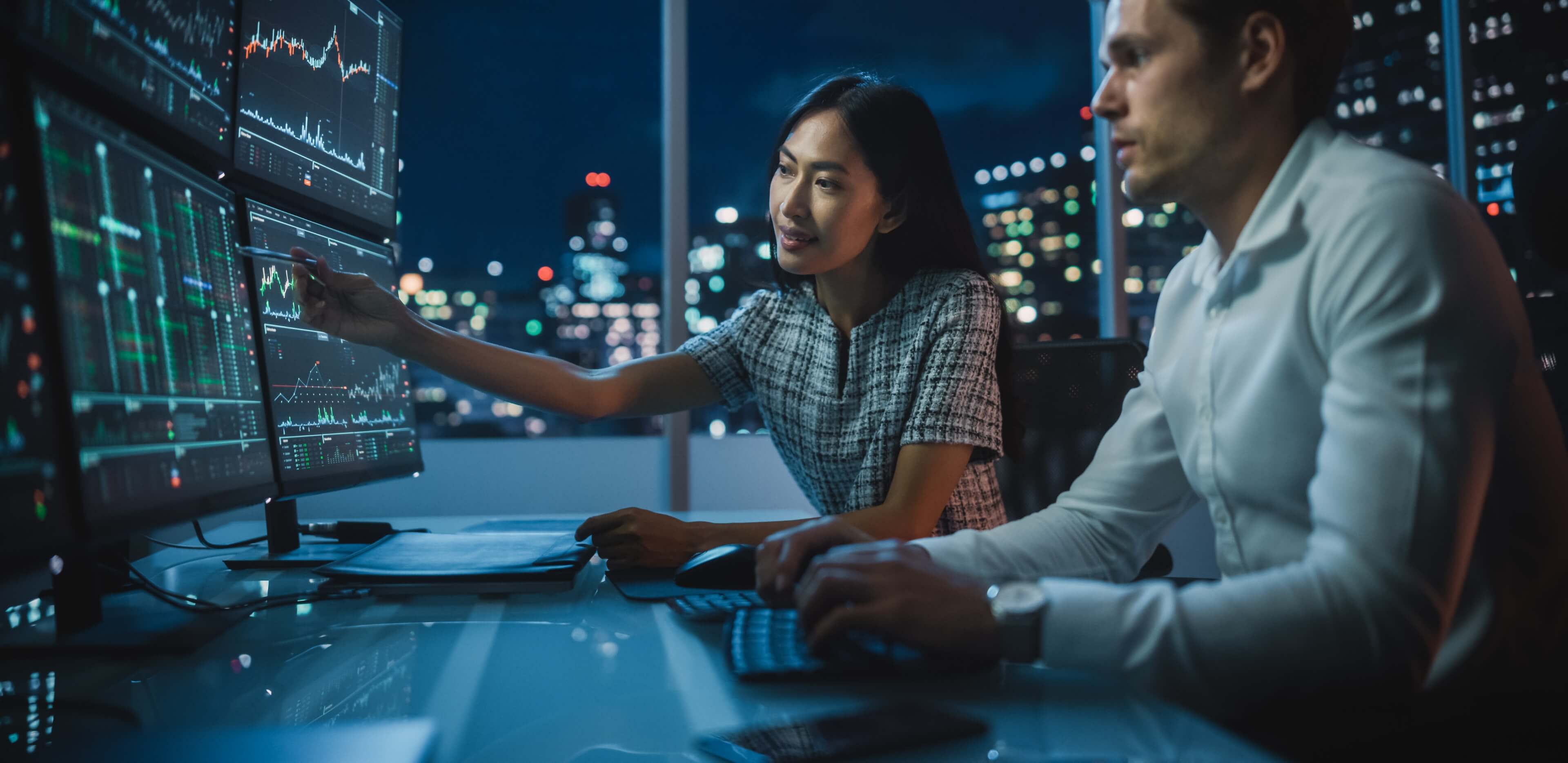 Analysts discussing financial data shown on computer screens